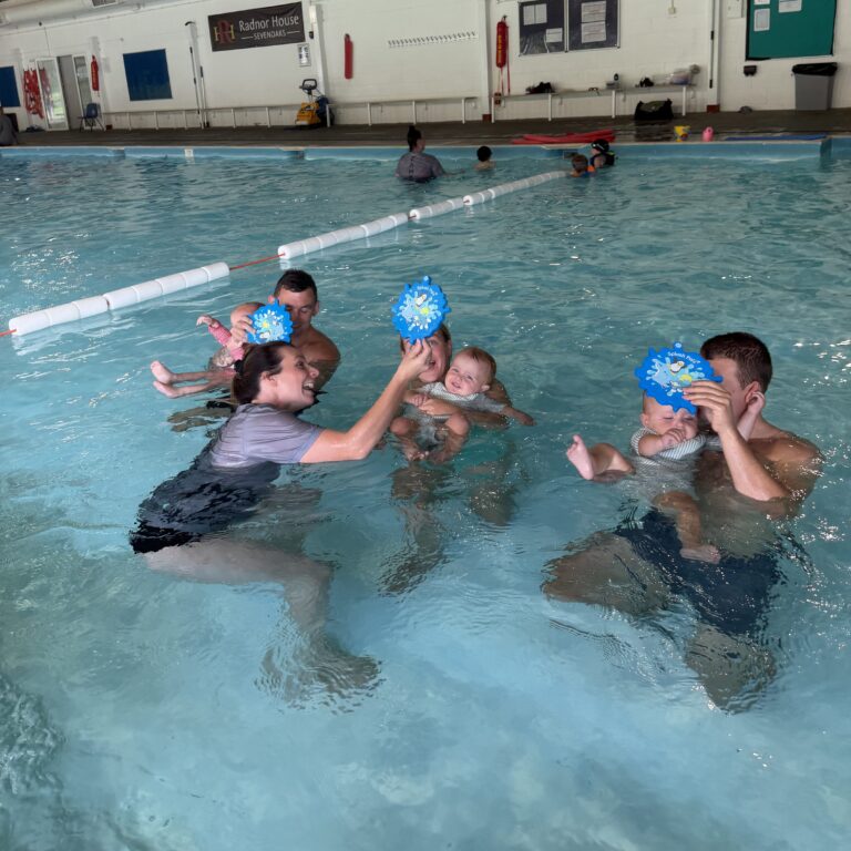 Parents and babies playing with balls in a swimming class